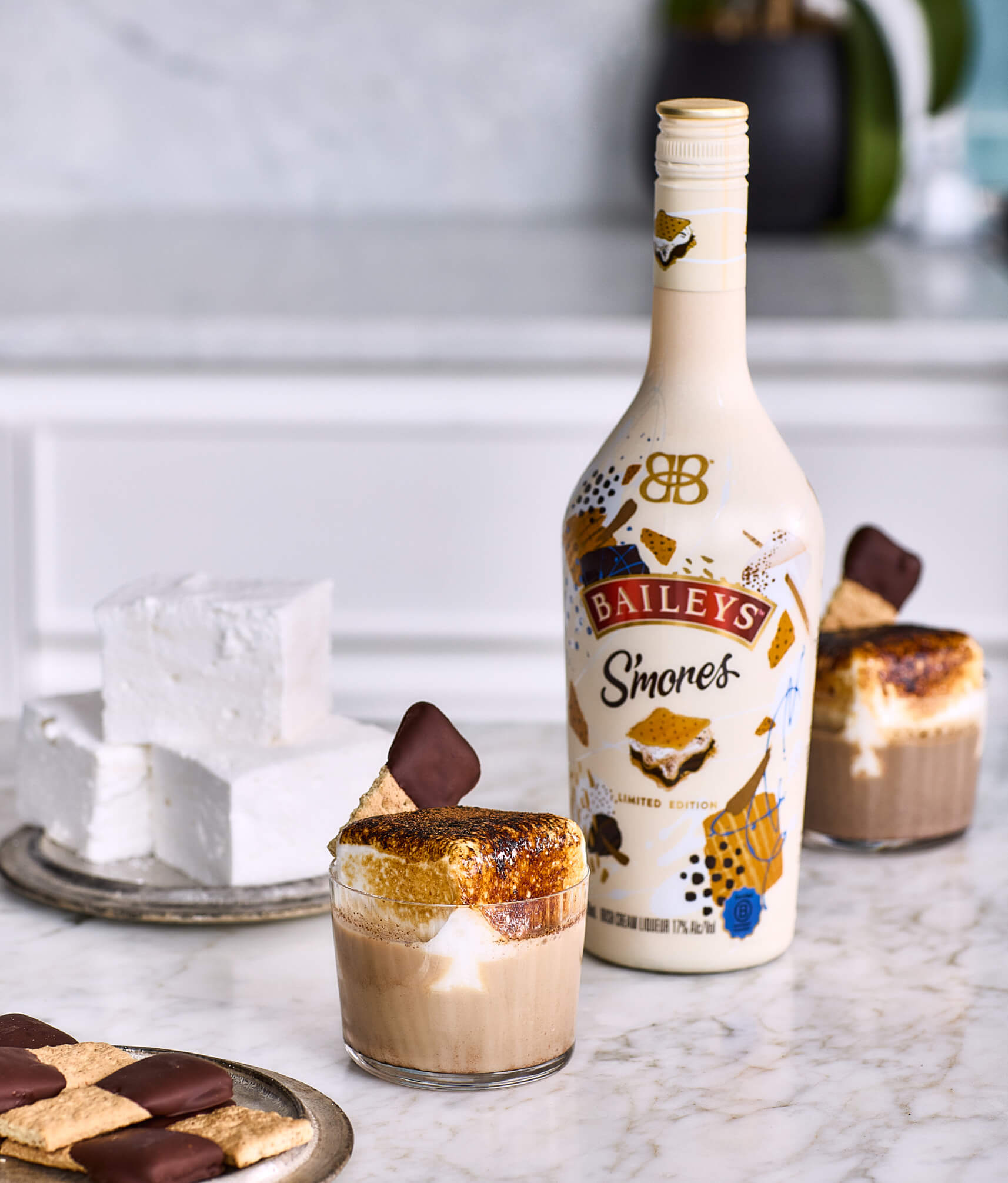 A glass of Baileys Roasted S'morestini with a bottle of Baileys S'mores